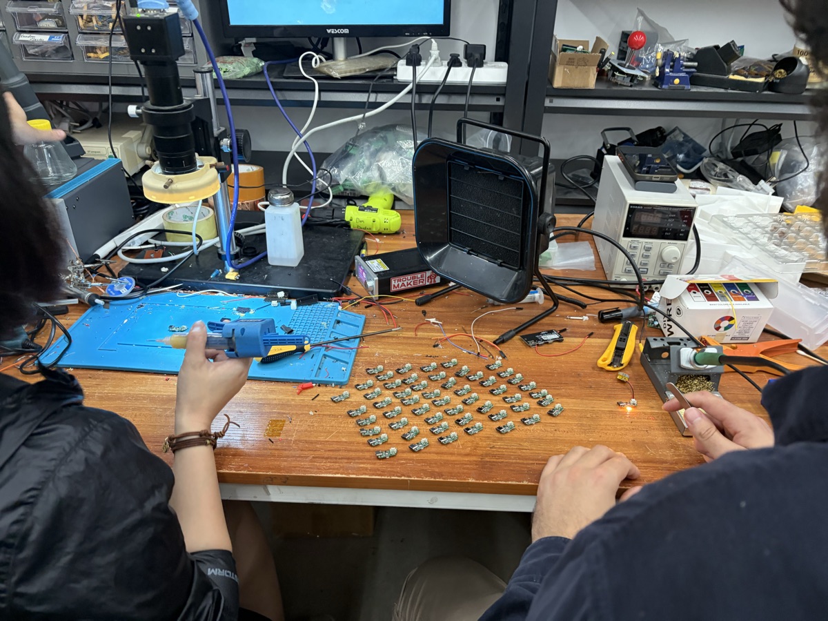 Hardware engineers programming chips at workbench in Troublemaker workspace, Shenzhen