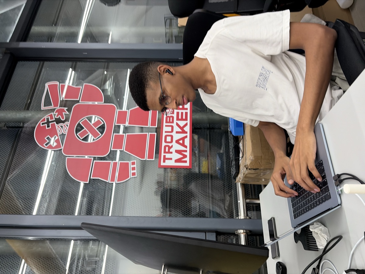 Working at desk with Troublemaker logo on glass, Huaqiangbei coworking space