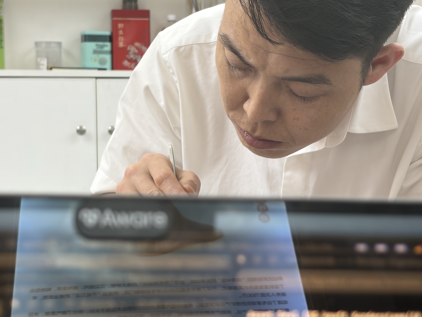 Specialist performing traditional xiujiao foot care with laptop in foreground
